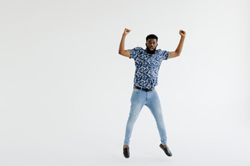 Portrait of a cheerful afro american man in headphones jumping isolated on a white background