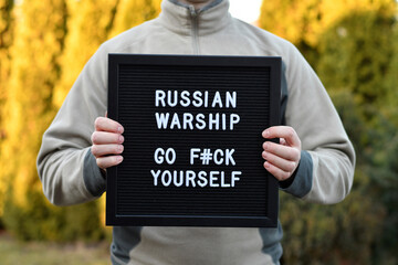 Man holding a letterbox with citation "Russian warship go f#ck yourself". War in Ukraine