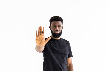 Portrait of serious African American male holding hand in stop sign, warning and preventing you...