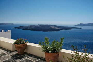 Panoramic view of the volcano Nea Kameni  from a rooftop decorated with flower pots in Santorini