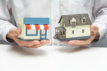 Pledge of a house for business. Secured loan. Choosing a shop or house. Businessman holding a house...