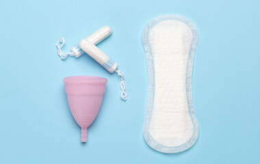 Menstruation. Pads and tampons, menstrual cup on a blue background.