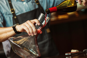 Sommelier pouring red wine into carafe to make perfect color