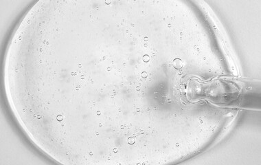 Transparent cosmetic gel with a pipette on a white background. Macro photo of gel structure with bubbles.