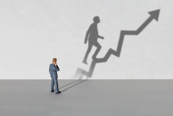 Businessman thinks how to succeed. Shadow from a businessman in the form of a growth chart as a...