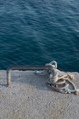 Choke chain on concrete ground by sea. Rusty metal. Vertical photo.