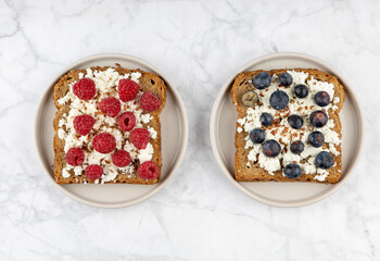 Obraz na płótnie Canvas Whole grain bread toasts with cottage cheese and fresh raspberries ,blueberries and with flax seeds, on a white background .Top view .Dieting concept .