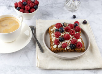 Whole grain bread toasts with cottage cheese and fresh raspberries ,blueberries and with flax seeds with cup of coffee , on a white background .Top view .Dieting concept .