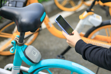 Hand using smartphone scanning the QR code of shared bike in city