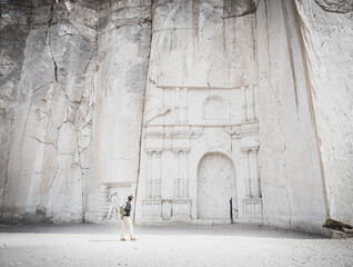 Wide angle view of a caucasian man looking at the stone wall sculpture of Petra in Ruta del Sillar,...