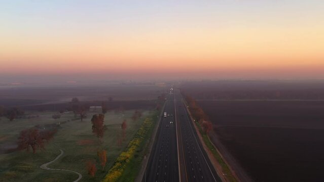 Cars and trucks on Highway 99 in the morning. Big rig trucks and cars drive along the scenic highway running across the Central Valley in California landscape at sunrise