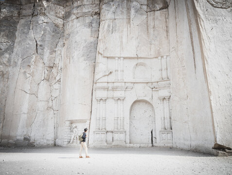 Wide angle view of a caucasian man looking at the stone wall sculpture of Petra in Ruta del Sillar, Arequipa, Peru.