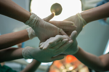 Asian surgeon and nurse with medical mask standing and join hand in operation theater at a...