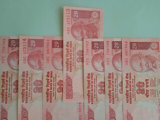 Red colored twenty rupees notes lined in a series on a green background