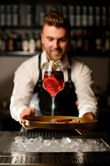 beautiful glass with delicious exclusive cocktail on tray in the hands of a male bartender