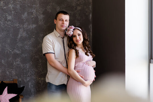 Profile side photo of sweet pretty adorable good mood couple expecting child sitting couch embracing belly inside indoors