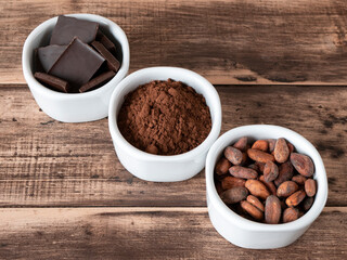Cocoa beans and sourced from them bitter chocolate and cocoa powder. Three bowls with cocoa products