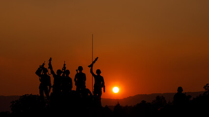 Fototapeta na wymiar silhouette group of special forces sodiers hold the guns on tanks to indicative of their victory with the sunset background