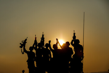 silhouette group of special forces sodiers hold the guns on tanks to indicative of their victory...