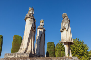 Statues of King Ferdinand, Queen Isabella and Christopher Columbus in the garden of the alcazar in Cordoba - obrazy, fototapety, plakaty