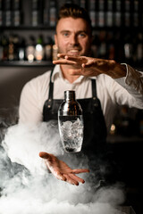 wonderful view of the glassy shaker in the air and the hands of male bartender near it.