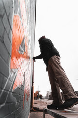 Side view of the artist drawing colorful graffiti on the wall of the building