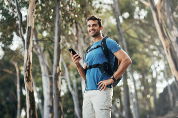 I just need to make an important call quick. Cropped shot of a cheerful young man texting on his cellphone while going for a hike up a mountain. - obrazy, fototapety, plakaty