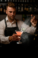 cocktail glass with alcoholic drink bartender holds in his hand and sprinkles on it