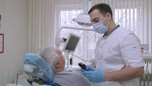 Male dentist making casts of elderly patient teeth to make removable dentures in dental office. Healthcare and dentistry business