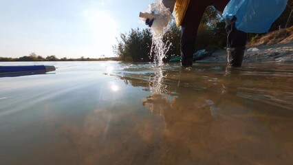 FPV on water closeup view of unrecognizable person collecting plastic rubbish leftovers in lake. Dirty lake cleaning. Nature conservation.