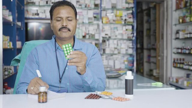 Pharmacist writing price or billing of medicines at retail medical shop couter - concept of small business owner and occupation