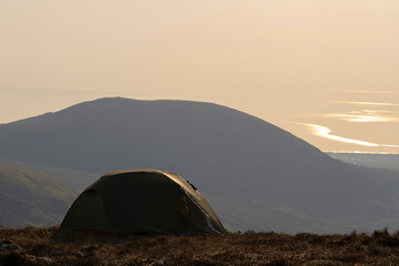 A wild camping tent high in the mountains at dusk
