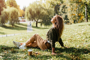Young caucasian woman resting carefree, relaxing on lawn on sunny day. Side view hipster woman with...