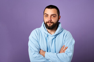 Happy bearded man wears blue sweater on violet background. friendly smile. Copy space