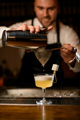 Fototapeta na wymiar hands of bartender gently strain the cocktail through a sieve into a glass