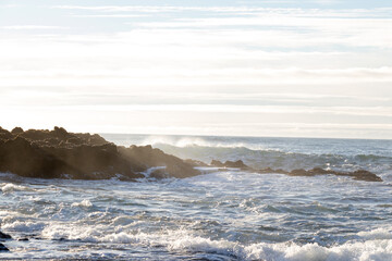 waves hitting rocks on the shore and beach