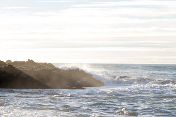 waves hitting rocks on the shore and beach