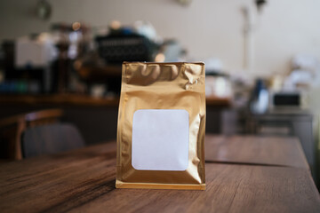 Golden packaging fresh brew coffee bean with empty label and cafe background