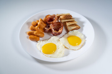 Western brekfast on isolated white background. Sunny side up eggs, sausage, vacom and toast bread.