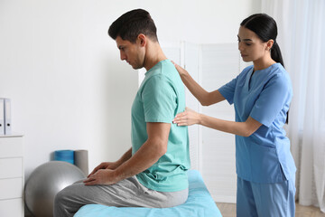 Orthopedist examining man's back in clinic. Scoliosis treatment