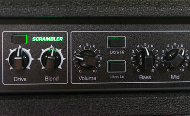 Details of a bass amp with knobs for volume, mix and other buttons to improve sound quality. The...