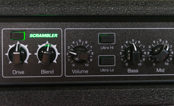 Details of a bass amp with knobs for volume, mix and other buttons to improve sound quality. The appliance has green lights
