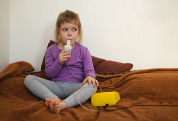 Sick child lies in bed and makes inhalation using a nebulizer.. Treatment of bronchitis, cough and...
