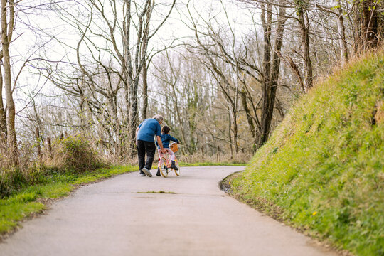 Anonymous grandfather teaching girl riding bicycle in countryside