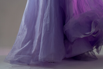 Сlose-up of a blue chiffon dress curiously bending on girl in the studio. Lavender fabric tulle...