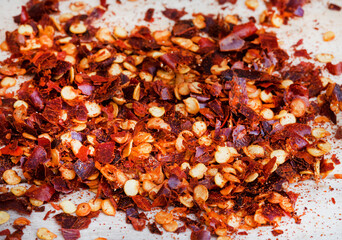 Dried red chili flakes on raw wooden surface