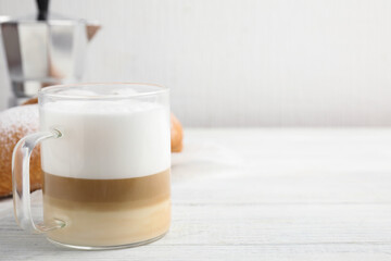 Delicious latte macchiato and croissant on white wooden table. Space for text