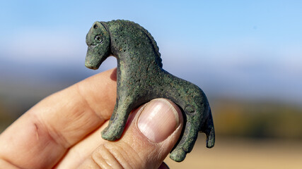 Closeup shot of a Bronze horse weight, Middle Ages, held in the hand