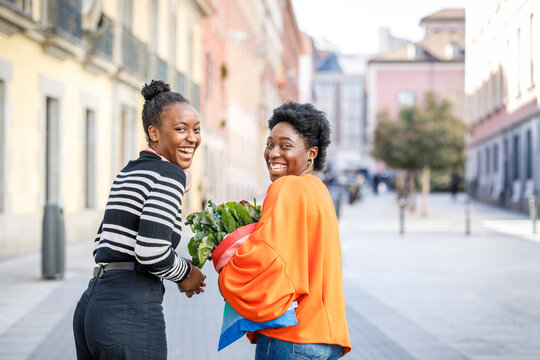 Cheerful black women walking on street