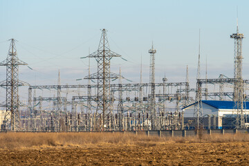 Electrical substation against blue sky and dried yellow grass.